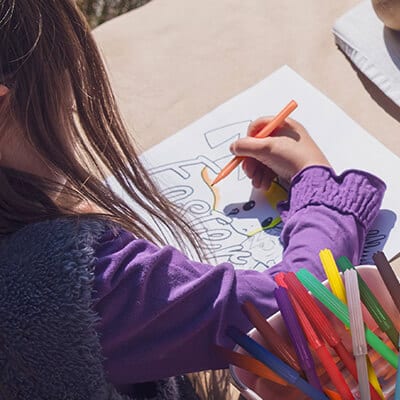 menina apoiada em uma mesa pintando desenho